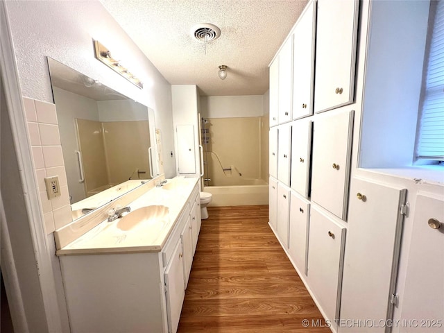 bathroom with visible vents, toilet, wood finished floors, a textured ceiling, and vanity