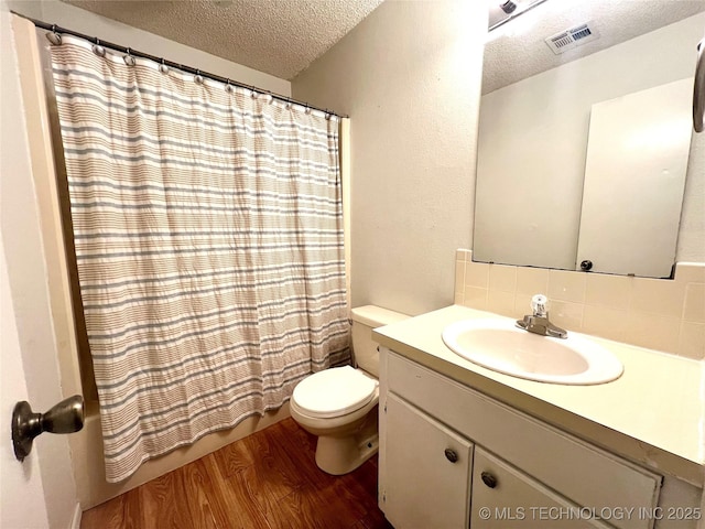 full bath with visible vents, toilet, vanity, a textured ceiling, and wood finished floors