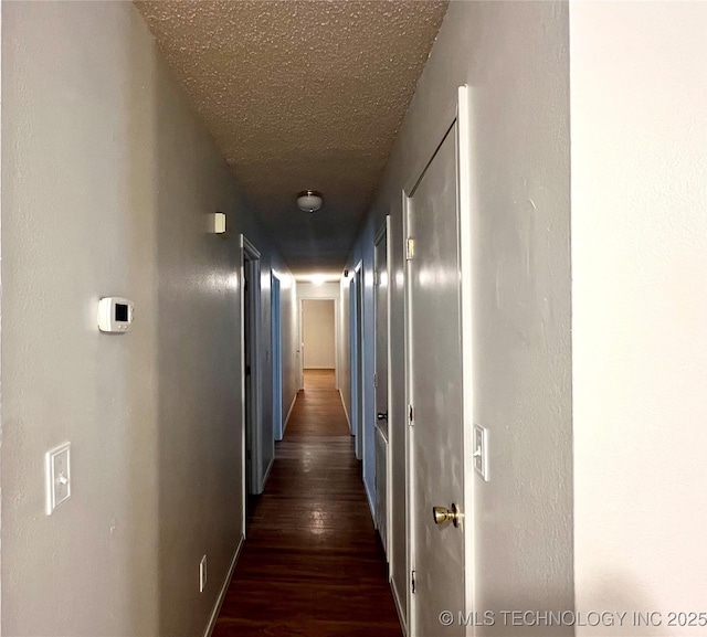 hall with a textured ceiling and wood finished floors