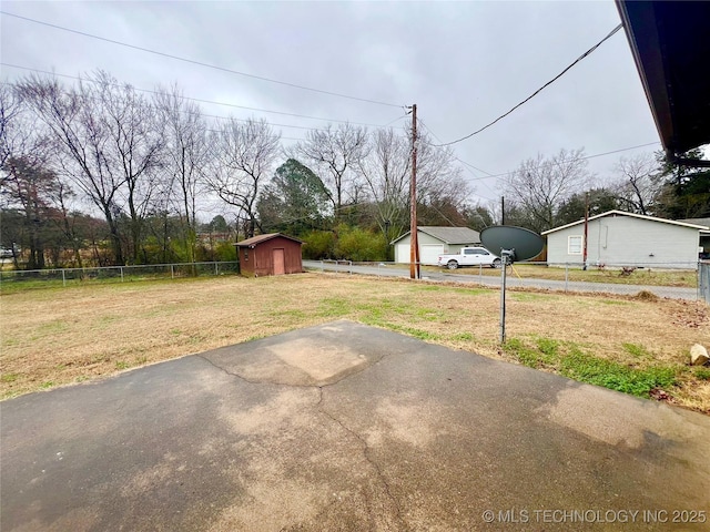 view of yard with a garage, a shed, fence, and an outbuilding