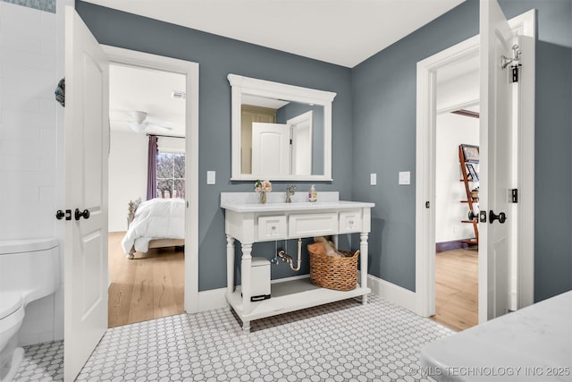 ensuite bathroom featuring toilet, vanity, baseboards, and ensuite bathroom