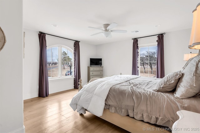 bedroom with light wood-style flooring, visible vents, and ceiling fan