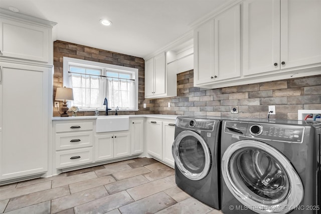 clothes washing area featuring separate washer and dryer, a sink, and cabinet space