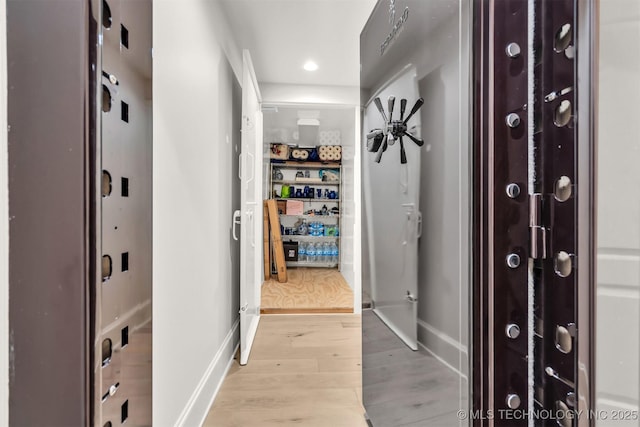 hallway featuring light wood finished floors, baseboards, and recessed lighting