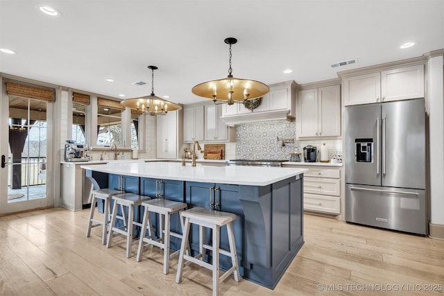 kitchen with tasteful backsplash, visible vents, light countertops, and stainless steel refrigerator with ice dispenser