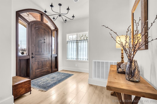 foyer entrance with arched walkways, wood-type flooring, visible vents, and baseboards