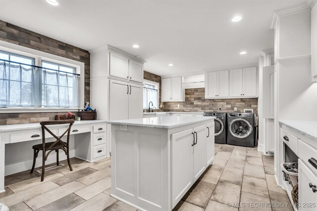 kitchen with tasteful backsplash, washer and clothes dryer, a kitchen island, white cabinetry, and a sink