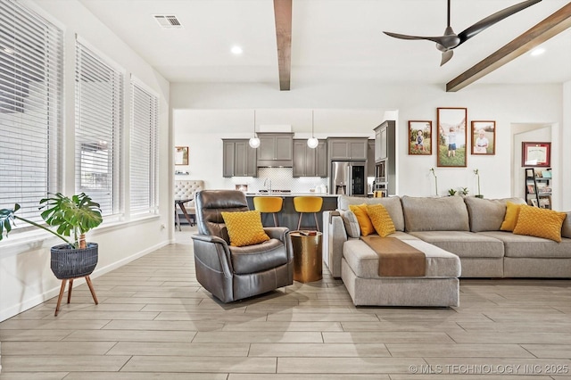 living room with ceiling fan, visible vents, light wood-style flooring, and beamed ceiling