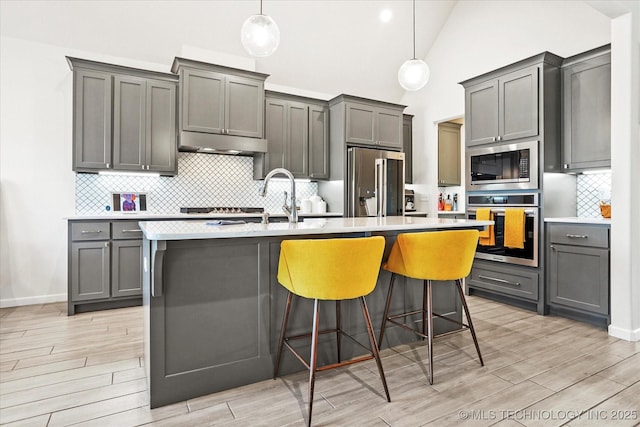 kitchen with stainless steel appliances, gray cabinets, light countertops, and wood tiled floor