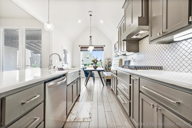 kitchen featuring wall chimney exhaust hood, appliances with stainless steel finishes, backsplash, and gray cabinetry