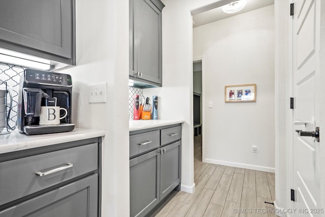 kitchen with light countertops, tasteful backsplash, wood finish floors, and gray cabinetry