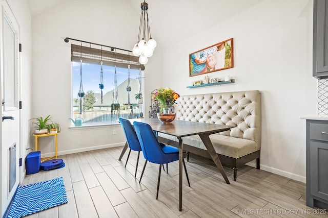 dining space with light wood-style flooring, baseboards, and a notable chandelier