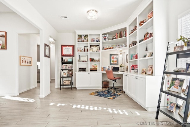 office space featuring built in desk, wood finish floors, visible vents, and baseboards