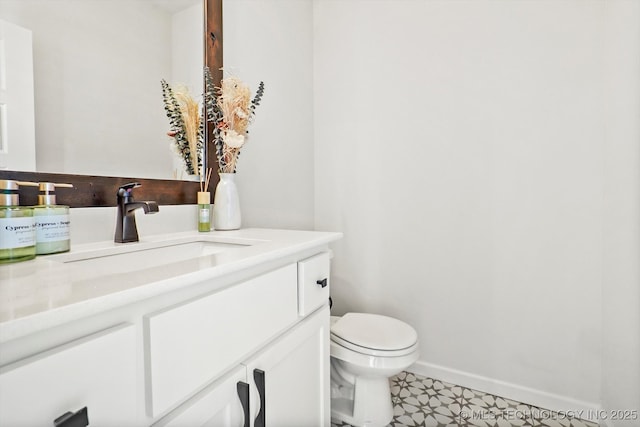 bathroom featuring toilet, baseboards, and vanity