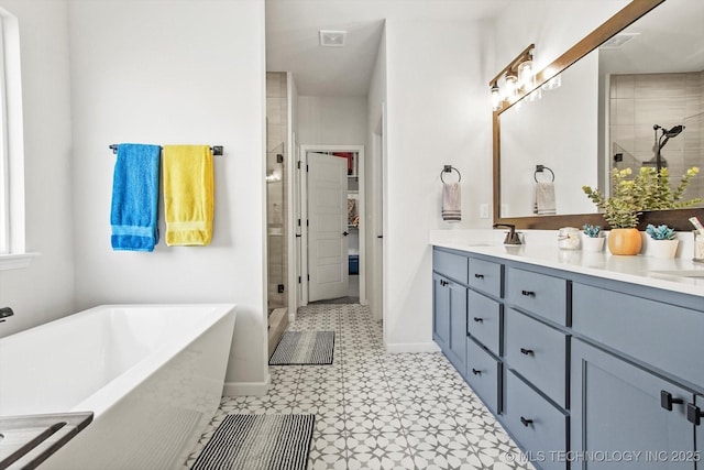 full bath featuring double vanity, baseboards, a soaking tub, a shower stall, and a sink