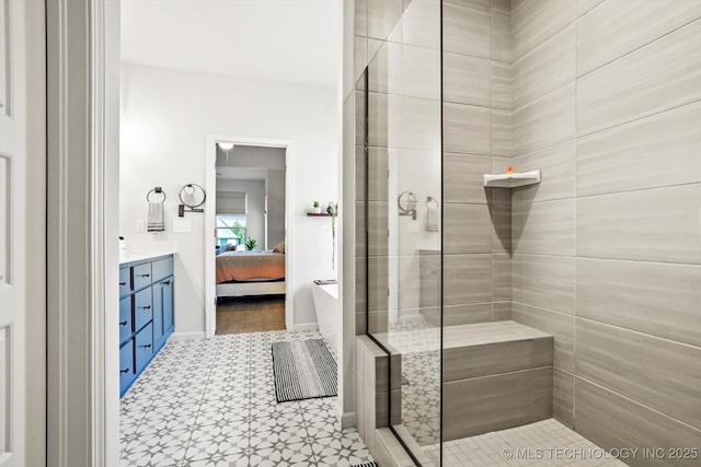 ensuite bathroom featuring baseboards, connected bathroom, a shower stall, and vanity