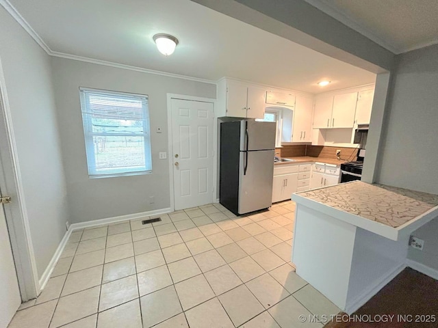 kitchen with black range with gas cooktop, ornamental molding, light tile patterned flooring, and freestanding refrigerator