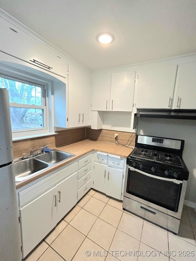 kitchen with crown molding, gas stove, freestanding refrigerator, and a sink