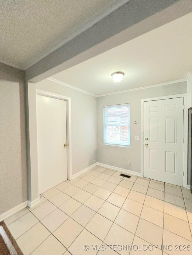 interior space with baseboards, light tile patterned flooring, visible vents, and crown molding