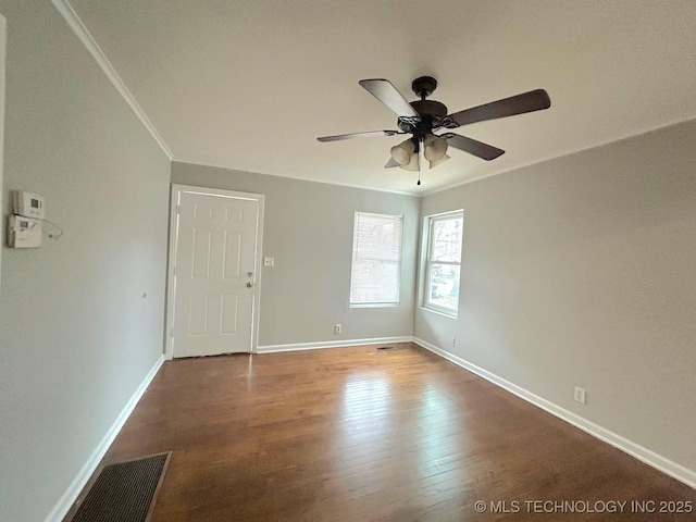 unfurnished room with crown molding, visible vents, a ceiling fan, wood finished floors, and baseboards