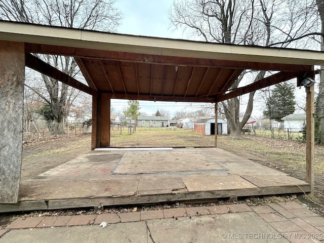 view of patio / terrace with an outdoor structure, fence, and a shed