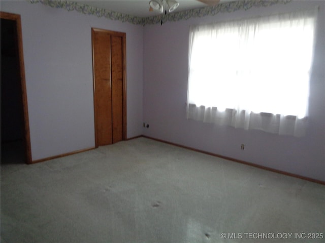 unfurnished room featuring carpet floors, baseboards, and a ceiling fan