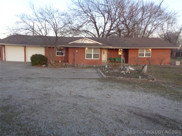 ranch-style home with an attached garage, aphalt driveway, and brick siding