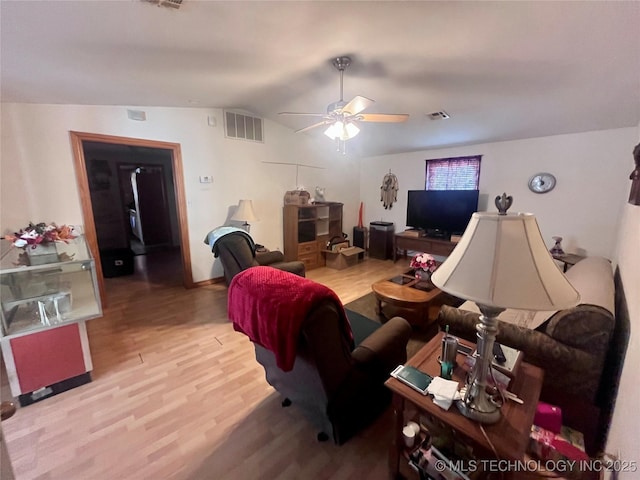 living room with vaulted ceiling, wood finished floors, visible vents, and a ceiling fan