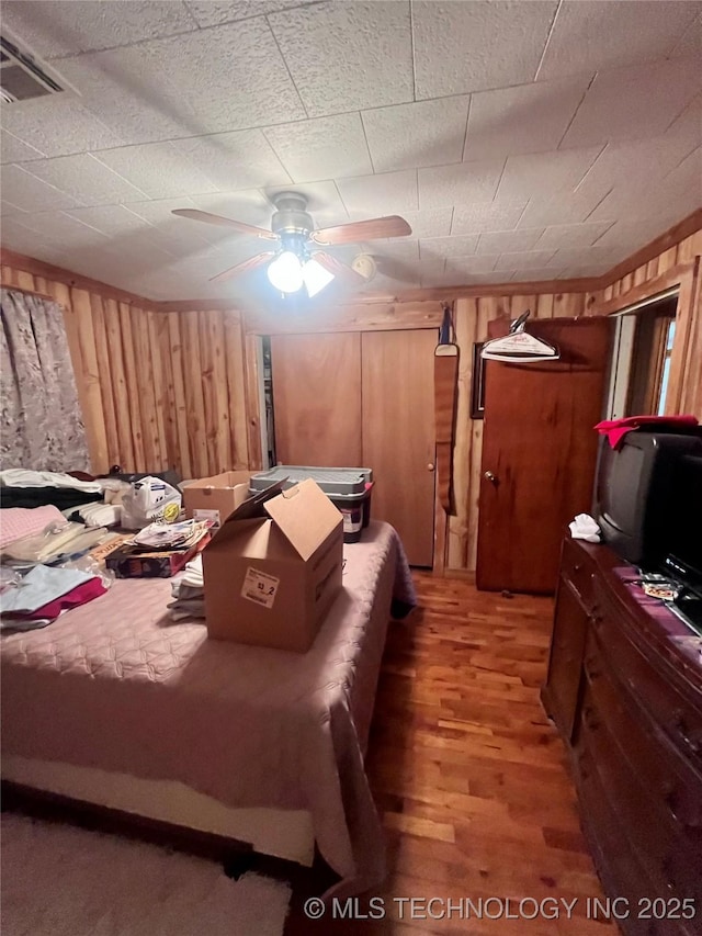 bedroom featuring visible vents, wood walls, and light wood-style flooring