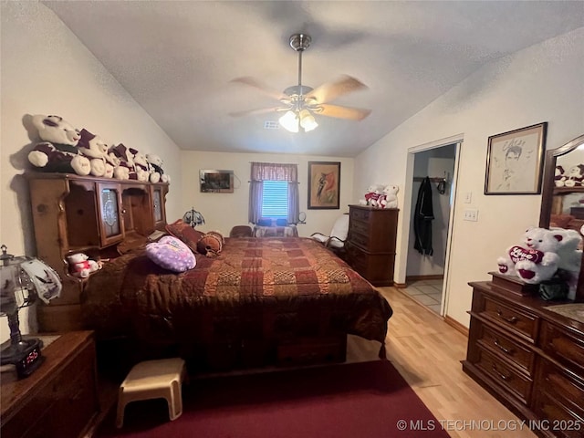 bedroom with light wood-style floors, ceiling fan, vaulted ceiling, and a textured ceiling
