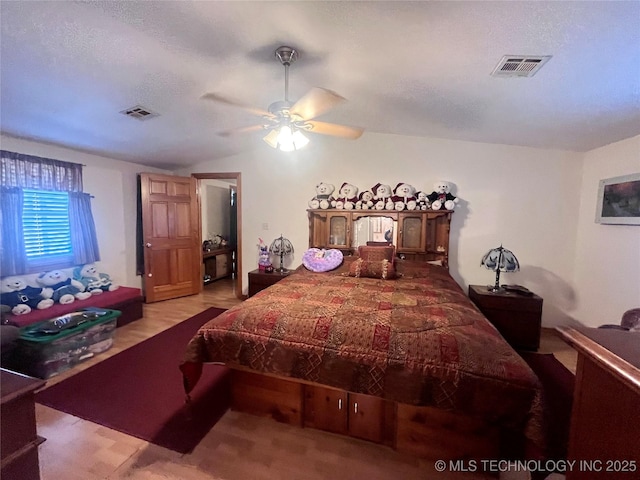 bedroom with lofted ceiling, ceiling fan, a textured ceiling, and visible vents