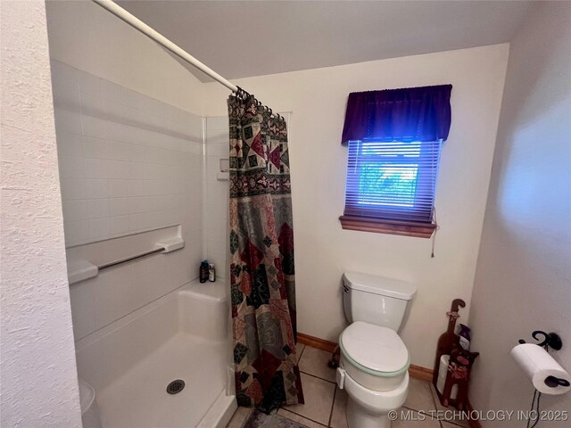 bathroom featuring baseboards, tile patterned flooring, toilet, and a shower stall