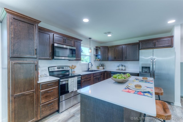 kitchen with dark brown cabinetry, visible vents, stainless steel appliances, light countertops, and a sink