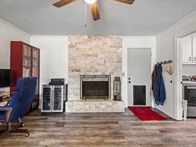 home office with washer / clothes dryer, wood finished floors, a stone fireplace, and ornamental molding