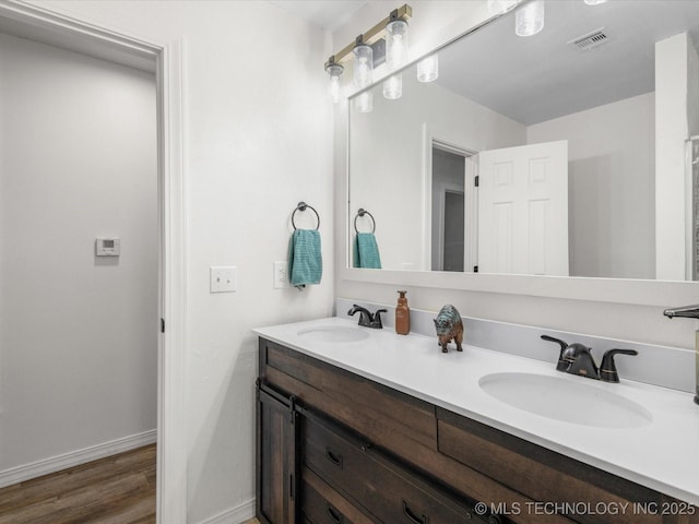 bathroom featuring double vanity, a sink, visible vents, and baseboards