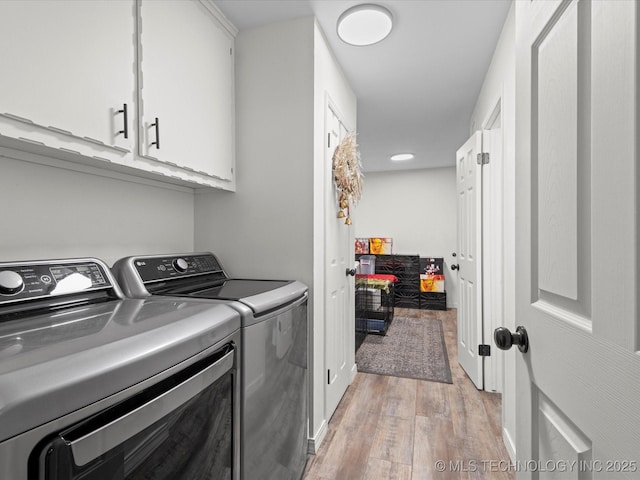 washroom featuring light wood-style flooring, washing machine and clothes dryer, and cabinet space