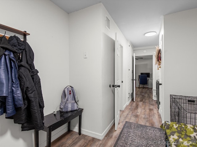 hallway with visible vents, baseboards, and wood finished floors