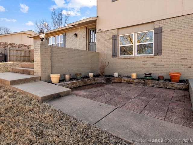 exterior space with crawl space, fence, a patio, and brick siding