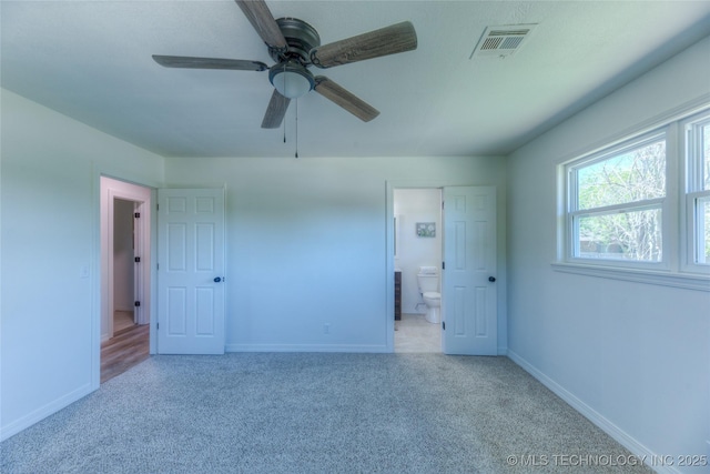 unfurnished bedroom featuring ensuite bathroom, carpet flooring, a ceiling fan, visible vents, and baseboards