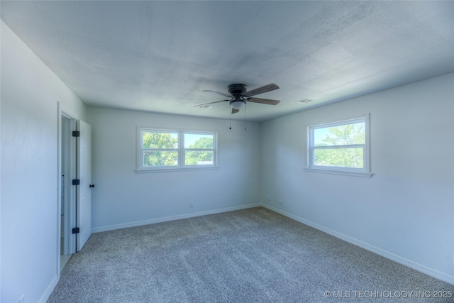 spare room featuring baseboards, carpet, visible vents, and a wealth of natural light