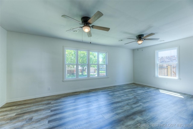 spare room featuring wood finished floors, a ceiling fan, baseboards, and a healthy amount of sunlight