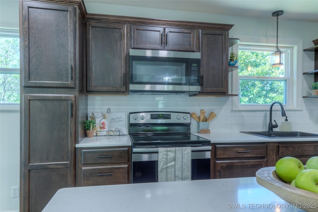 kitchen with stainless steel appliances, light countertops, a sink, dark brown cabinetry, and decorative backsplash