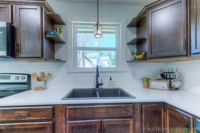 kitchen featuring stainless steel appliances, a sink, dark brown cabinets, backsplash, and open shelves