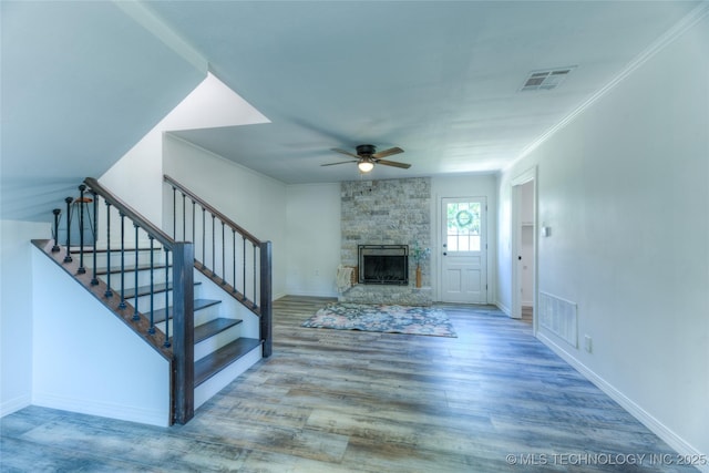 unfurnished living room with wood finished floors, a ceiling fan, visible vents, and stairway