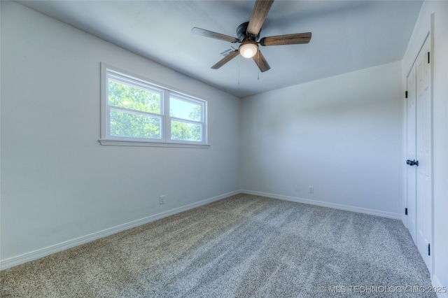 carpeted spare room featuring baseboards and a ceiling fan