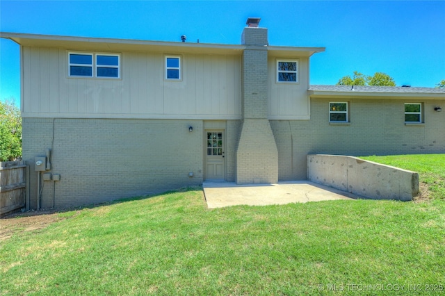 rear view of house featuring fence, a chimney, brick siding, and a yard