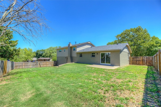 rear view of property with a fenced backyard, a chimney, brick siding, a lawn, and a patio