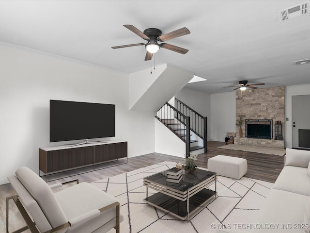 living area with wood finished floors, a ceiling fan, visible vents, and stairway