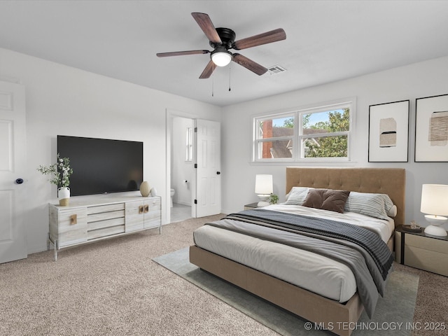 carpeted bedroom with ensuite bath, visible vents, and ceiling fan