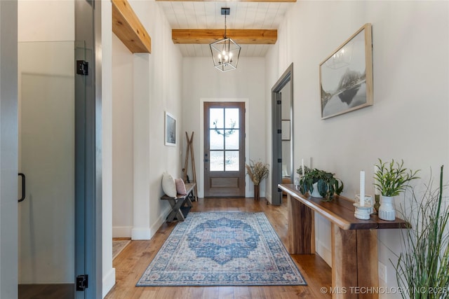 foyer featuring baseboards, wooden ceiling, beamed ceiling, light wood-style floors, and a chandelier